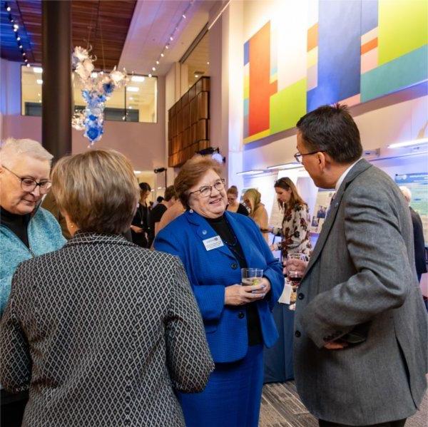 reception with four people standing talking with colorful artwork in the background